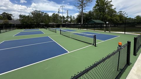 Row of blue and green outdoor pickleball courts with nets set up for play on a sunny day